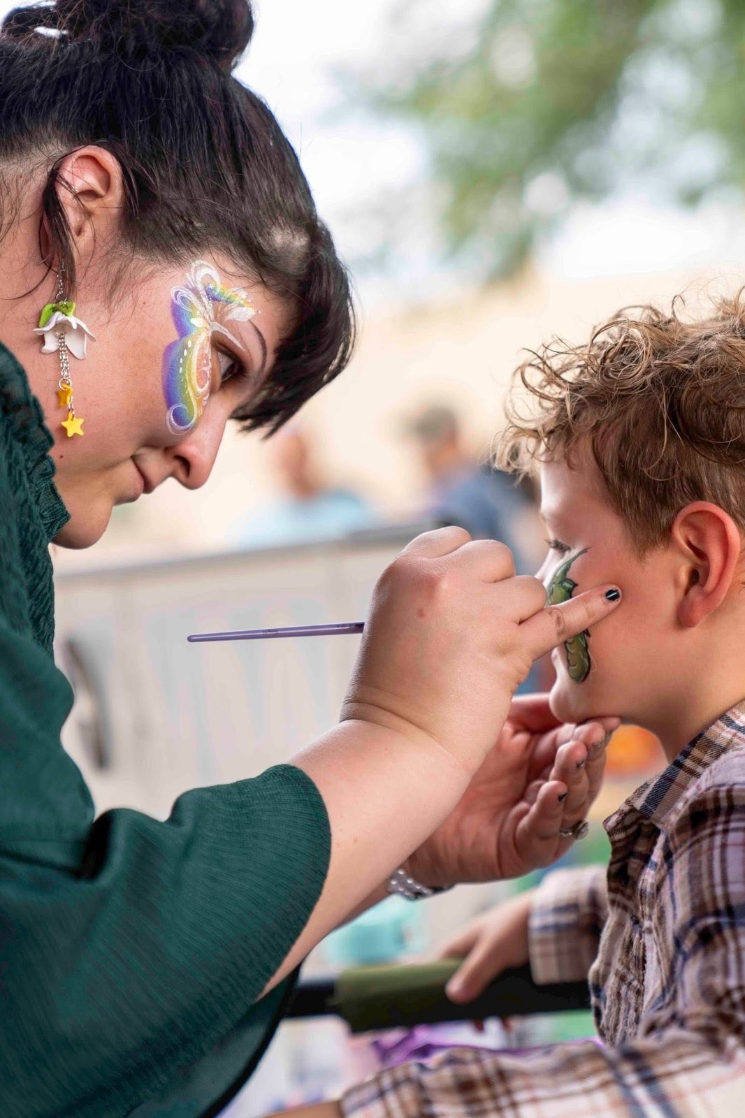 Sarah carefully painting a design on a child's face